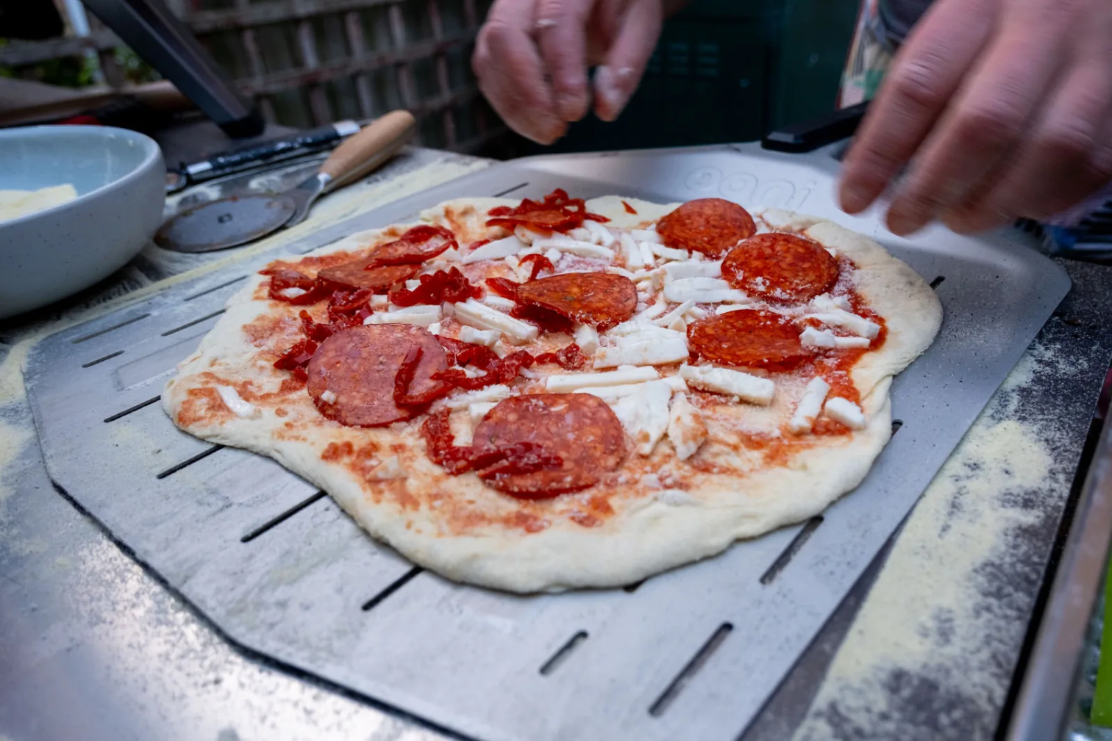 A cook sliding a pizza into the oven on a peel
