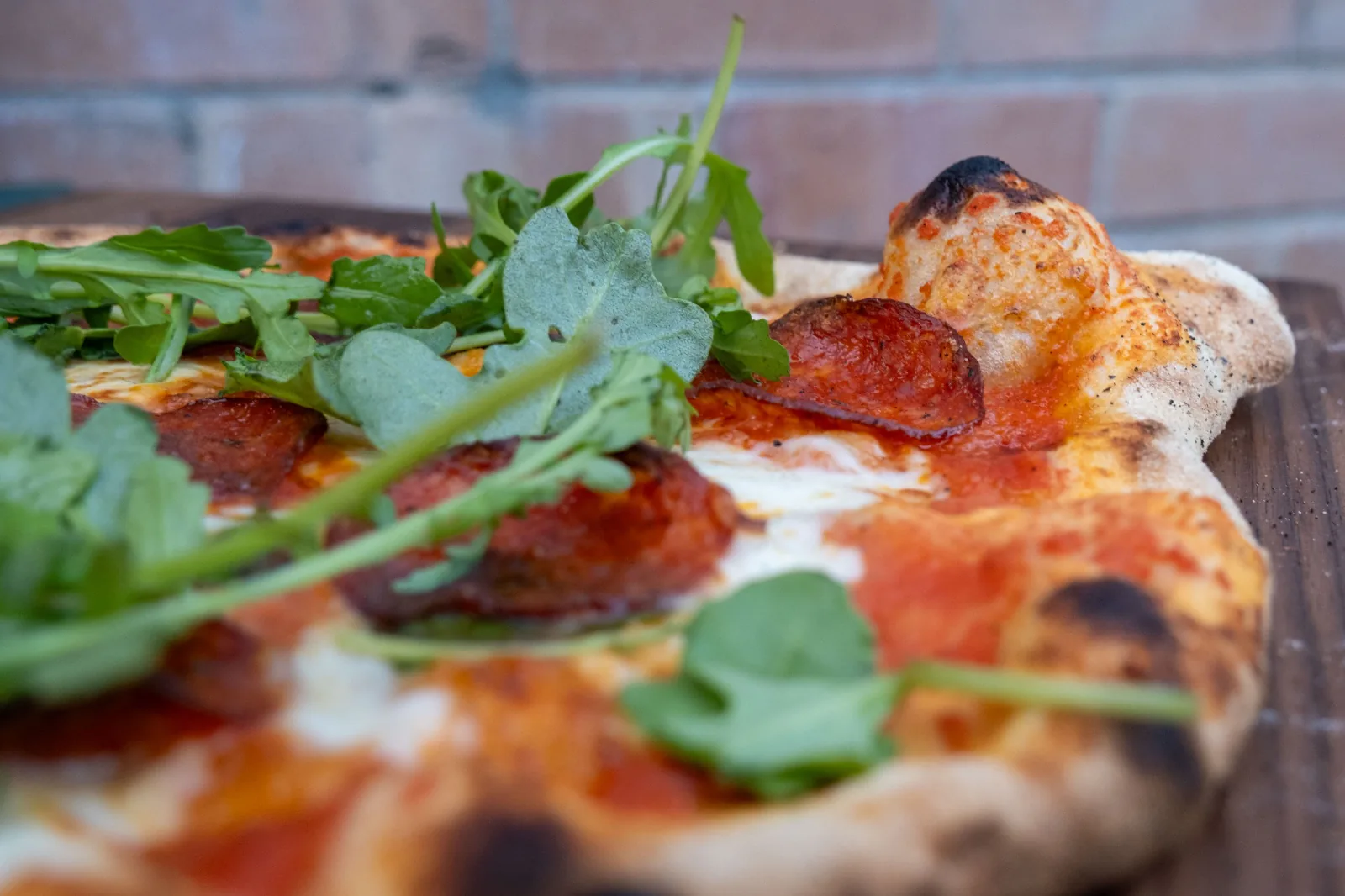 A finished pepperoni pizza topped with rocket, fresh from the oven