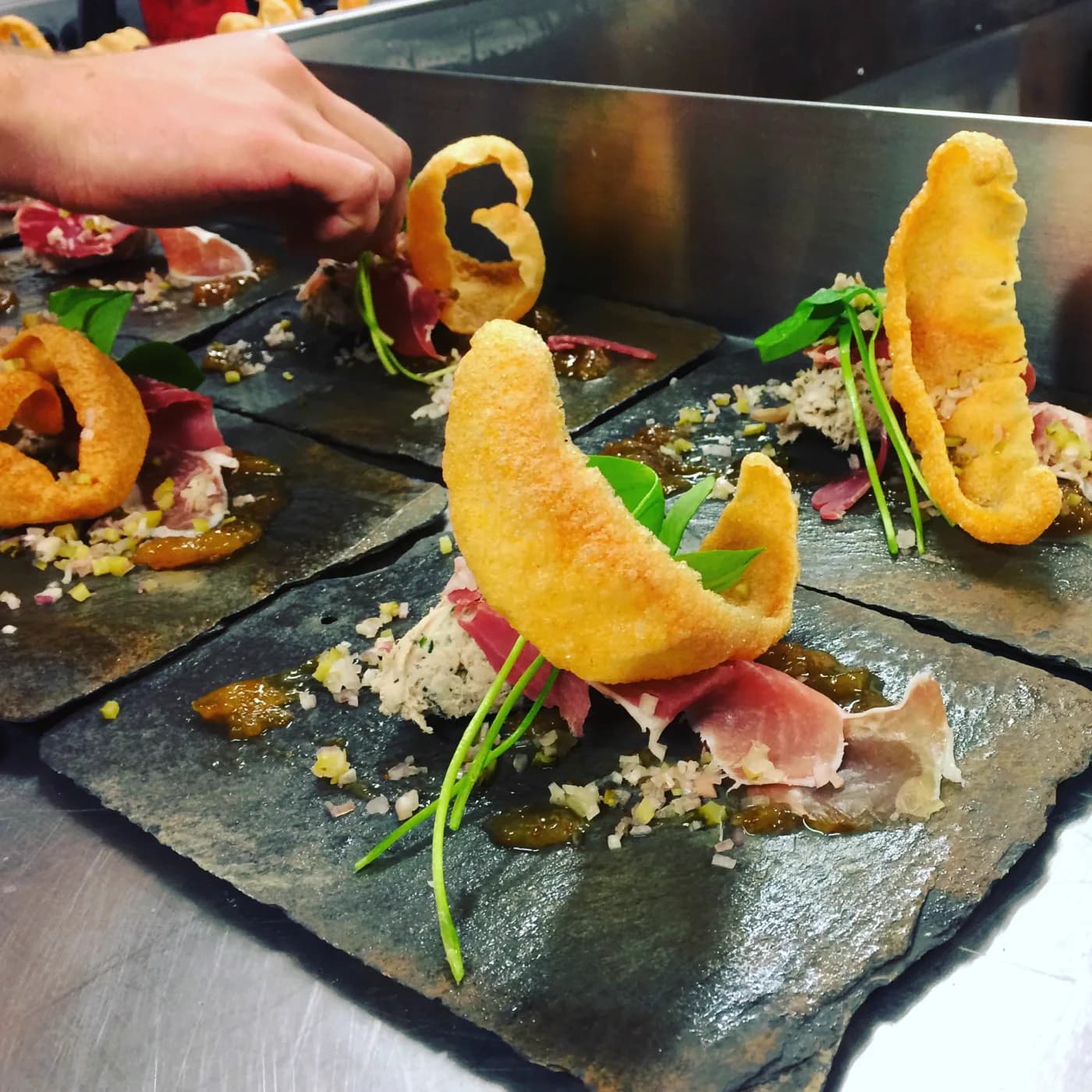 A cook holding a plated course in a dark kitchen